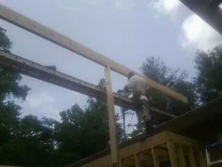 Carpenter setting a ridge beam over a new addition frame — Ice Dam Removal by Roofing Brothers in Hingham