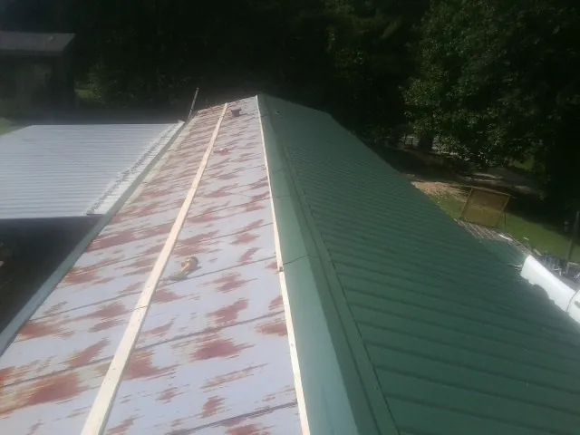 Old rusted panels beside newly installed green metal roofing — Wind Damage Roof Repair by Roofing Brothers in Hingham