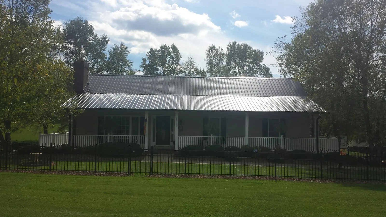 Gray metal roof on a brick ranch with a full width front porch — Gutter Guard Installation work by our crew in Hingham