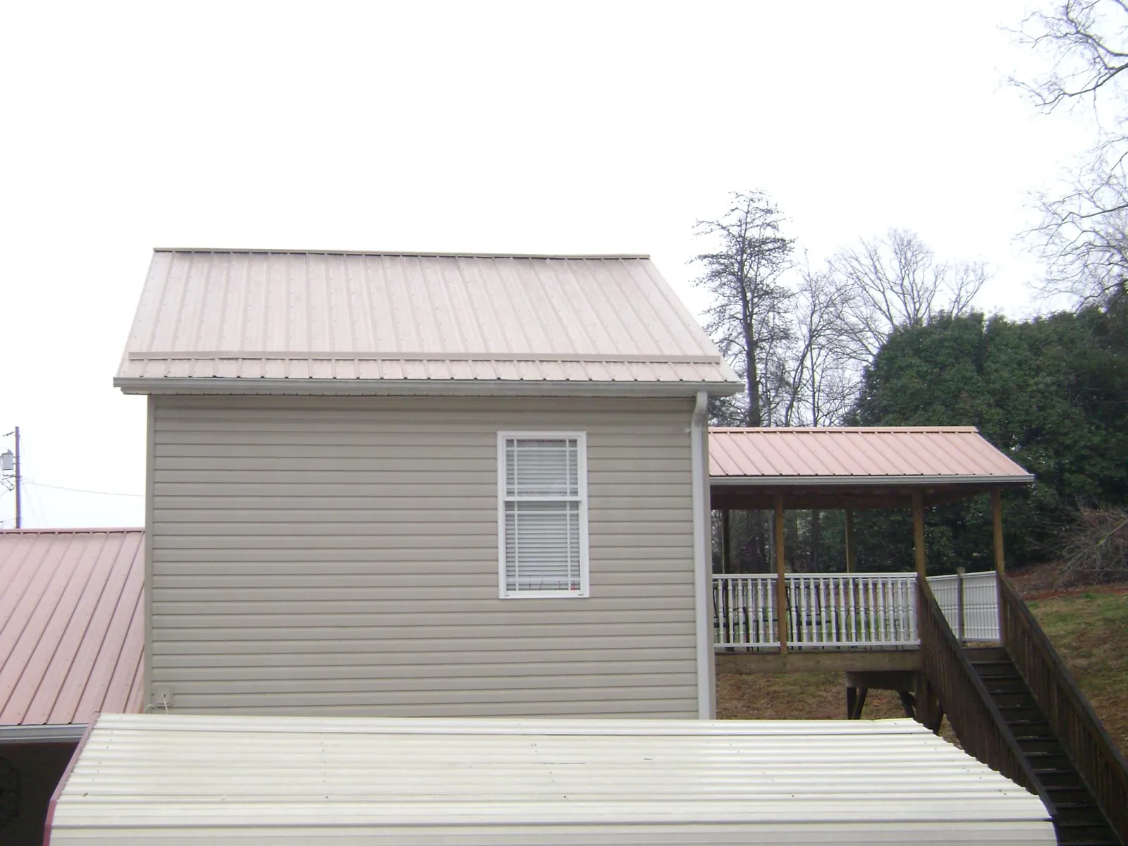 Tan metal roofs on a two story addition and attached porch, from a Roof Replacement job in Hingham